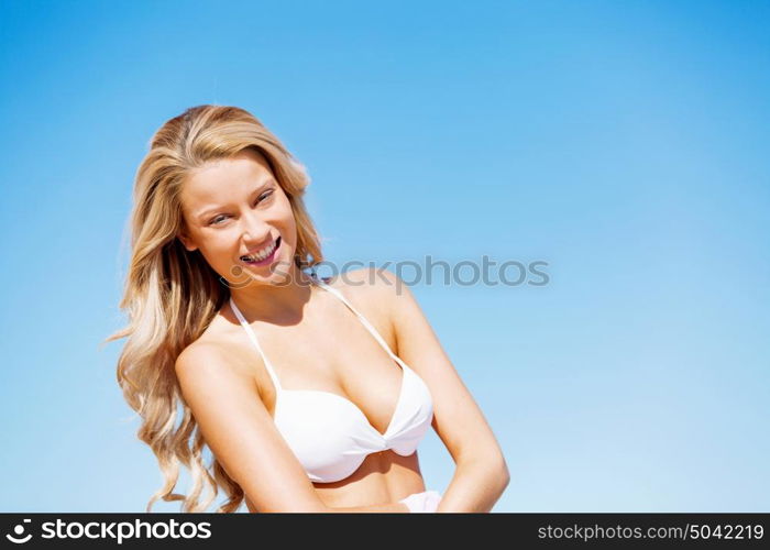 Young woman relaxing on the beach. Portrait of young pretty woman in white bikini relaxing on sandy beach