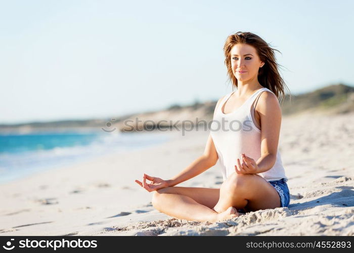 Young woman relaxing on the beach. Portrait of young pretty woman relaxing and meditating on sandy beach