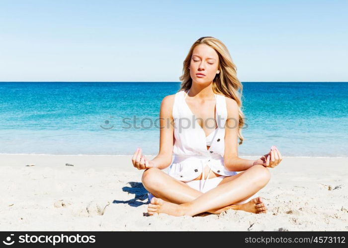 Young woman relaxing on the beach. Portrait of young pretty woman relaxing and meditating on sandy beach