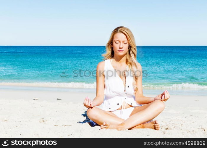 Young woman relaxing on the beach. Portrait of young pretty woman relaxing and meditating on sandy beach