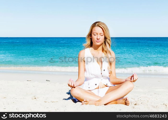 Young woman relaxing on the beach. Portrait of young pretty woman relaxing and meditating on sandy beach