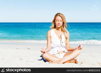 Young woman relaxing on the beach. Portrait of young pretty woman relaxing and meditating on sandy beach