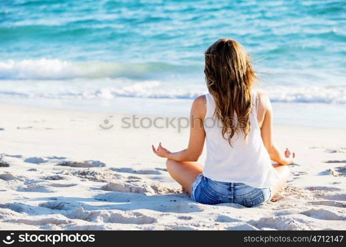 Young woman relaxing on the beach. Portrait of young pretty woman relaxing and meditating on sandy beach