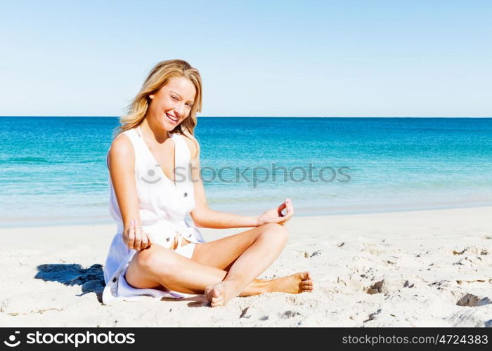 Young woman relaxing on the beach. Portrait of young pretty woman relaxing and meditating on sandy beach