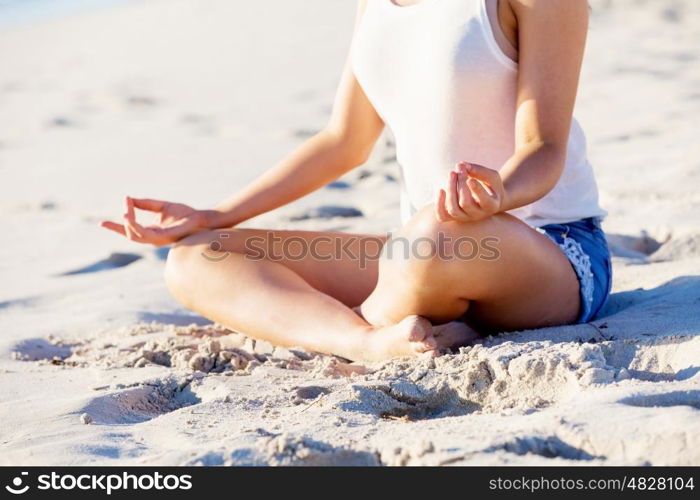 Young woman relaxing on the beach. Portrait of young pretty woman relaxing and meditating on sandy beach