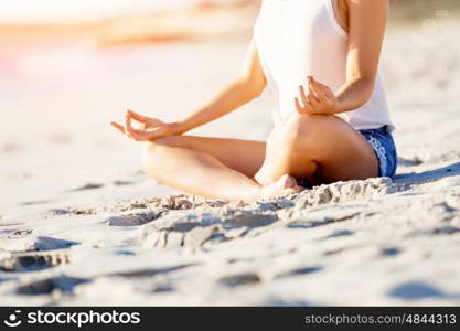 Young woman relaxing on the beach. Portrait of young pretty woman relaxing and meditating on sandy beach