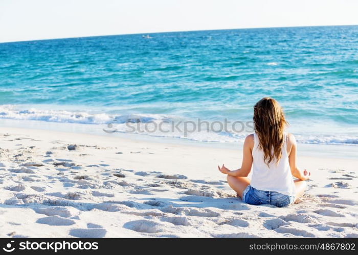 Young woman relaxing on the beach. Portrait of young pretty woman relaxing and meditating on sandy beach