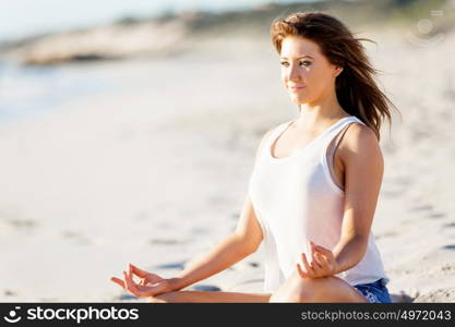 Young woman relaxing on the beach. Portrait of young pretty woman relaxing and meditating on sandy beach