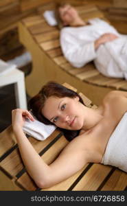 Young woman relaxing on wooden chair at luxury spa