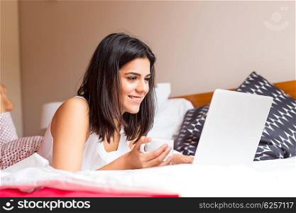 Young woman relaxing with her computer in bed