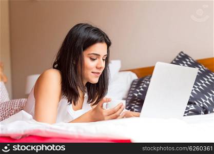 Young woman relaxing with her computer in bed