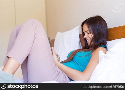 Young woman relaxing with her smartphone in bed