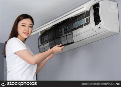 young woman removing air filter of the air conditioner for cleaning at home