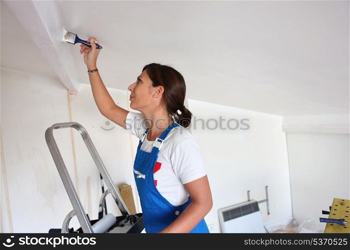Young woman repainting ceiling