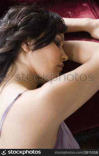 Young woman resting against sofa