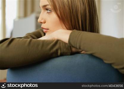 Young woman resting on back of chair