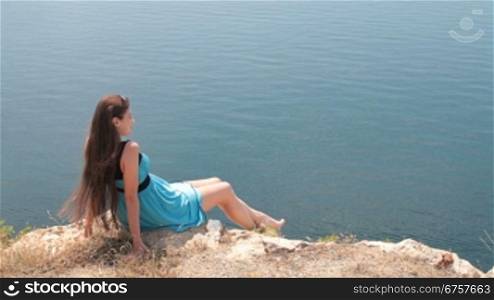 young woman resting on edge of cliff by the sea