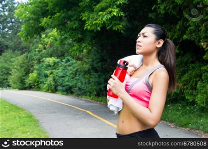 Young woman resting with towel and water bottle after running