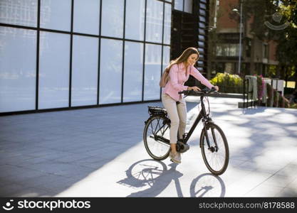 Young woman riding an electric bicycle in urban environment