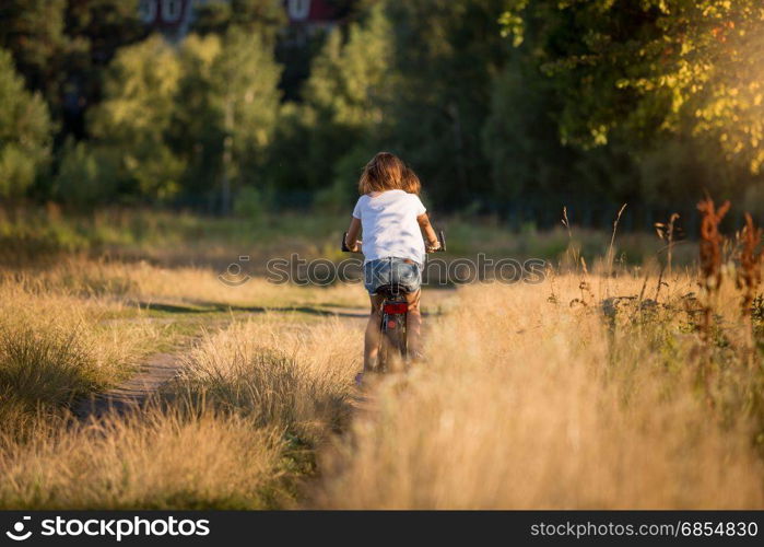 Young woman riding bicycle at meadow on dirt road