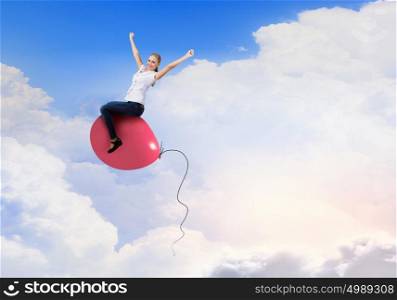 Young woman riding colorful balloon in sky. Woman riding balloon