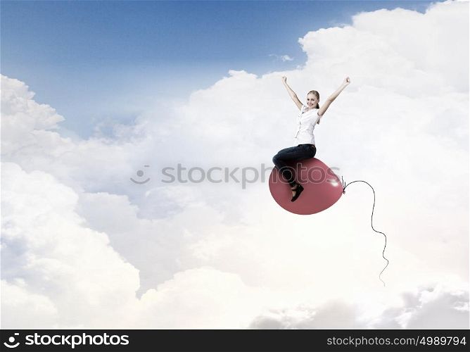 Young woman riding colorful balloon in sky. Woman riding balloon