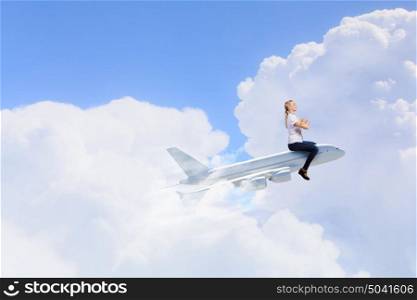 Young woman riding drawn airplane flying in air. Woman ride airplane