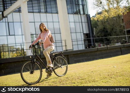 Young woman riding e bike in urban enviroment at sunny day