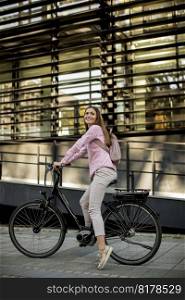 Young woman riding e bike in urban enviroment at sunny day