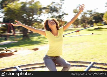 Young Woman Riding On Roundabout In Park