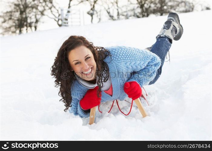 Young Woman Riding On Sledge In Snowy Landscape