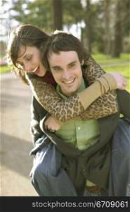 Young woman riding piggyback on a young man