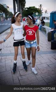 Young woman roller skating and another young woman walking with her, Malecon, Santo Domingo, Dominican Republic