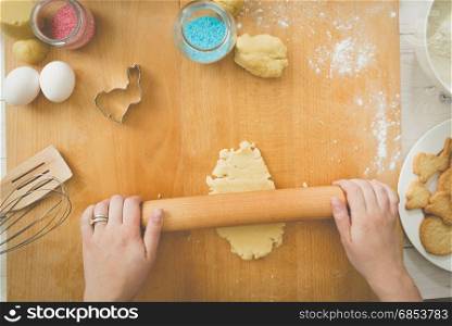 Young woman rolling dough on wooden board