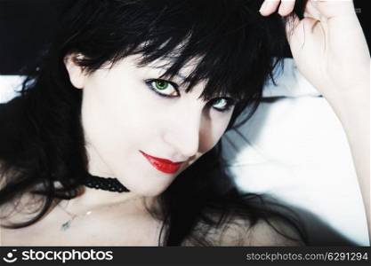 young woman&rsquo;s face with black hair, red lips and green eyes
