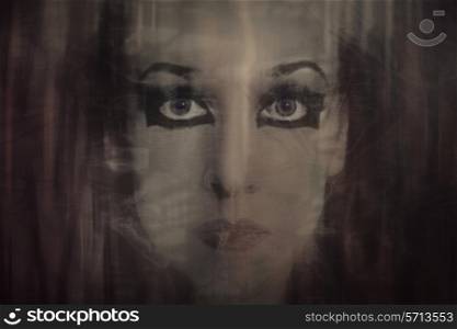 Young woman&rsquo;s face with gothic makeup through the transparent thin fabric