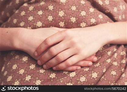 Young woman&rsquo;s folded hands in bed