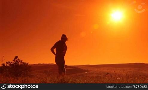 Young woman runner doing stretching exercises outdoors at sunrise
