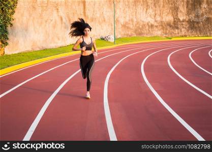 Young woman runner running race on athletics track.