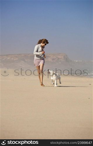 Young woman running and playing with her cute labrador retriever puppy 