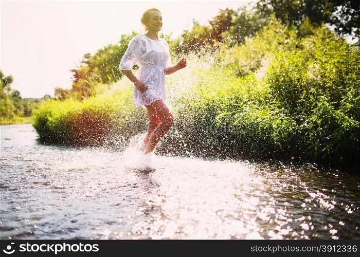 Young woman running in shallow water. Summertime.
