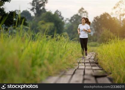 young woman running on wooden path in field
