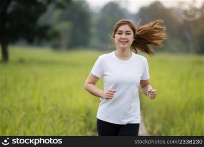 young woman running on wooden path in field