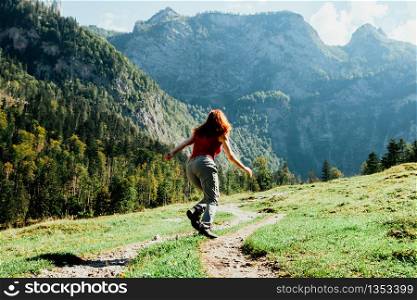 Young woman running through the path among mountains