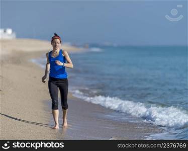 young woman runs on a seashore sandy beach in the morning