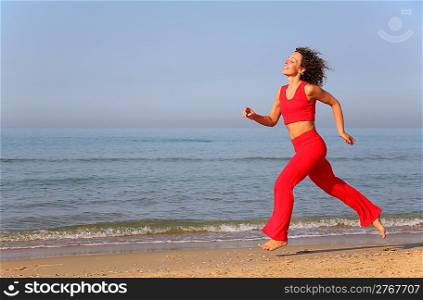 Young woman runs on shore of sea