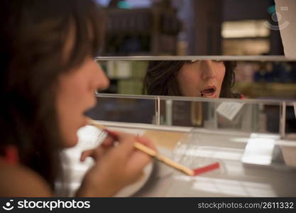 Young woman sampling lip gloss in beauty supply store