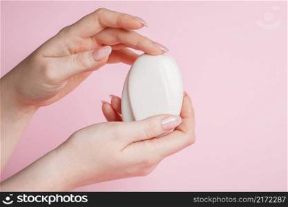 Young woman sanitizes hands with antibacterial soap on a pink background. Coronavirus prevention, health care.. Woman sanitizes hands with antibacterial soap on a pink background. Coronavirus prevention, health care.