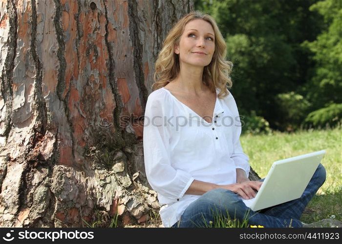 Young woman sat by tree