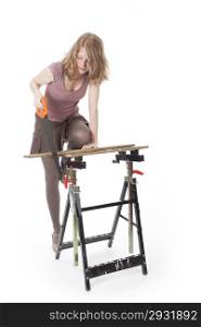 young woman sawing wood with hand saw